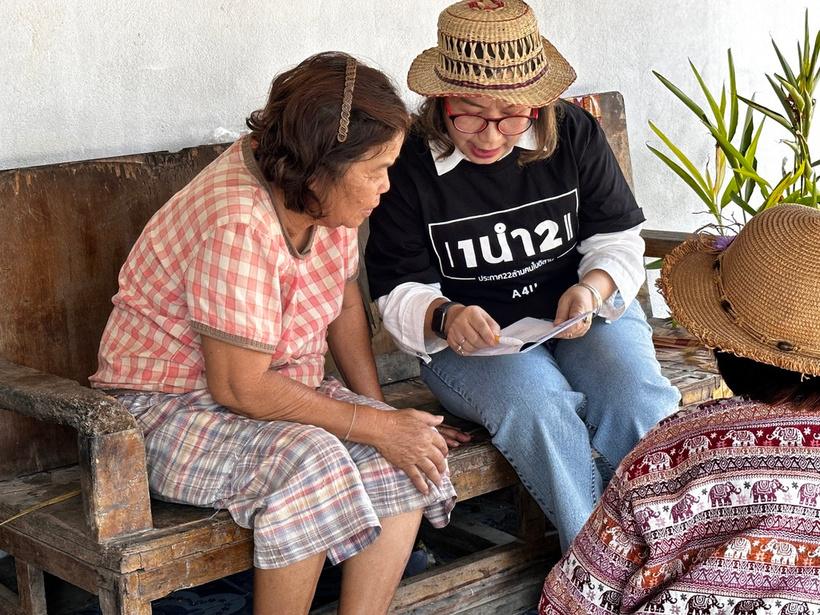Two women read a Gospel booklet together on a wooden bench