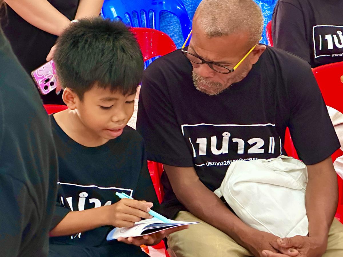 A boy shows a Gospel booklet to an older man