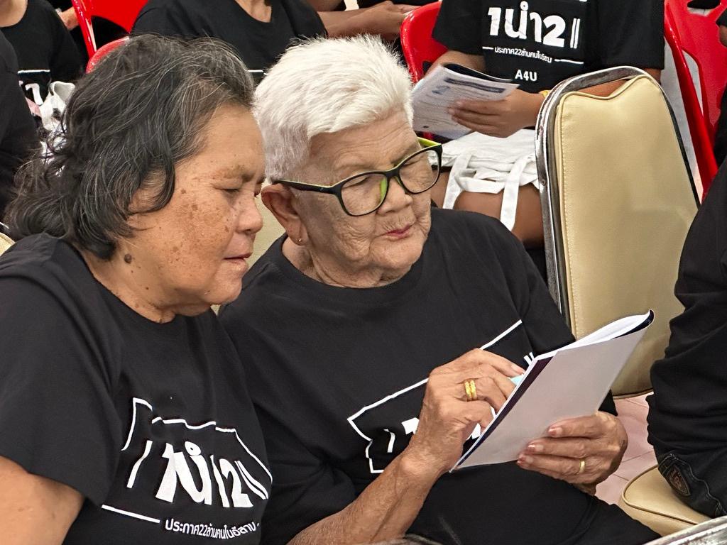 Two elderly women study a Gospel booklet together
