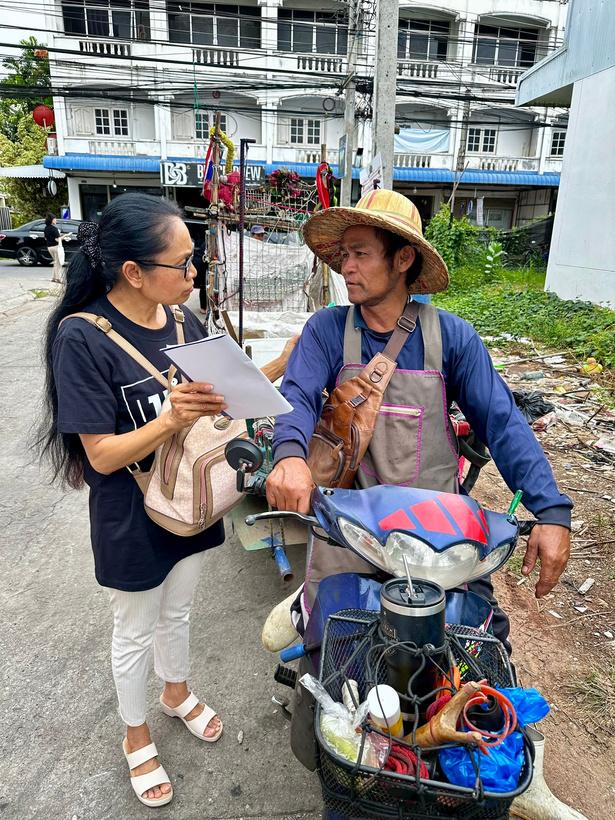 A 1นำ2 volunteer reads a Gospel booklet with a street vendor on his motorbike